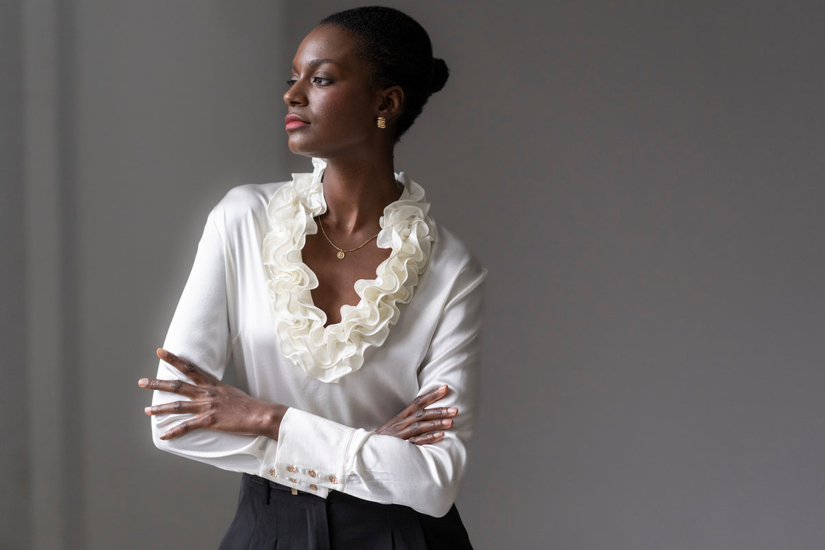 Woman wearing an ivory silk blouse with ruffled neckline