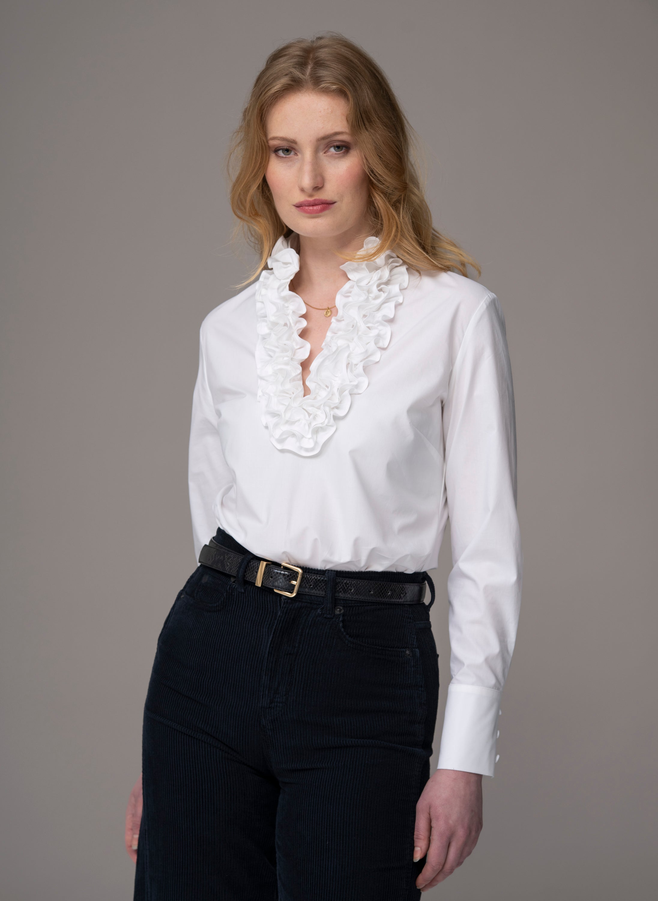 Woman wearing a white blouse with ruffled details by The Shirt Company