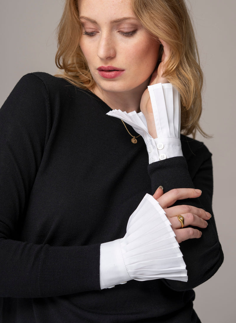 Woman wearing white pleated sleeves  or poignets plissé with black wool top
