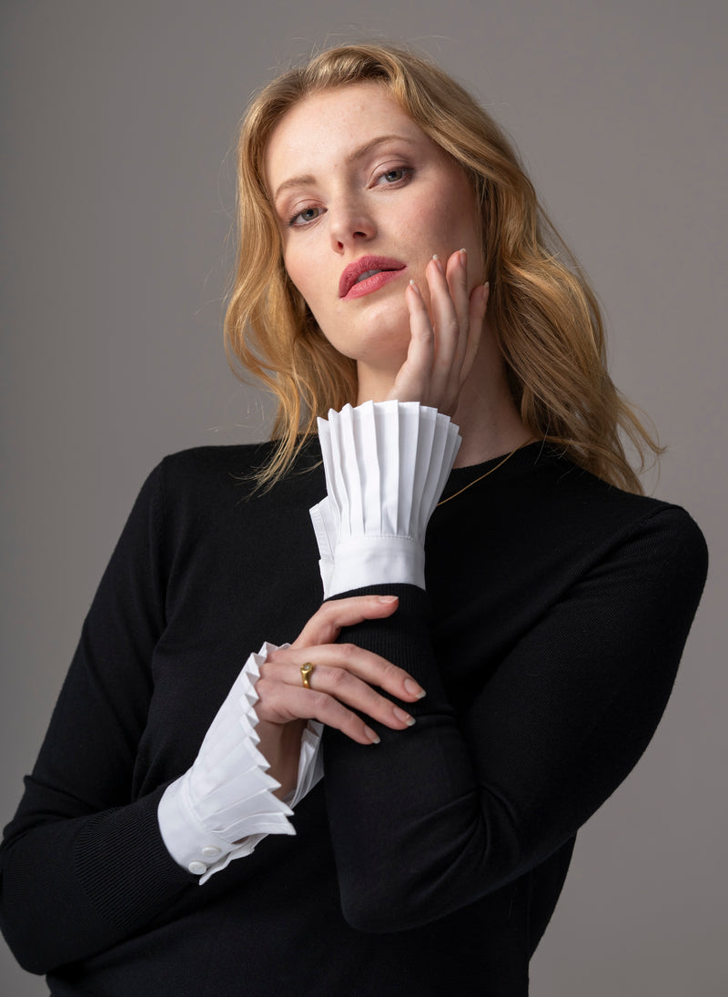 Woman wearing white pleated sleeves  or poignets plissé with black wool top
